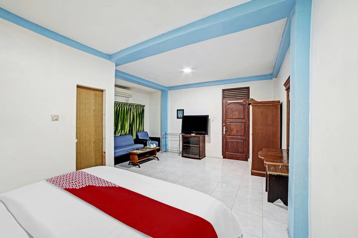 A hotel room with a bed, a TV, a sofa, and a wooden cabinet.