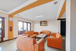 Un salon avec des canapés en cuir orange, une table basse et un tableau accroché au mur.