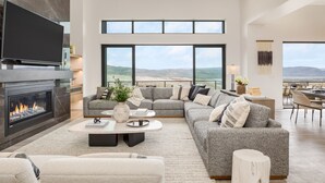 Ein modernes Wohnzimmer mit Kamin, großen Fenstern und Blick auf die Landschaft.