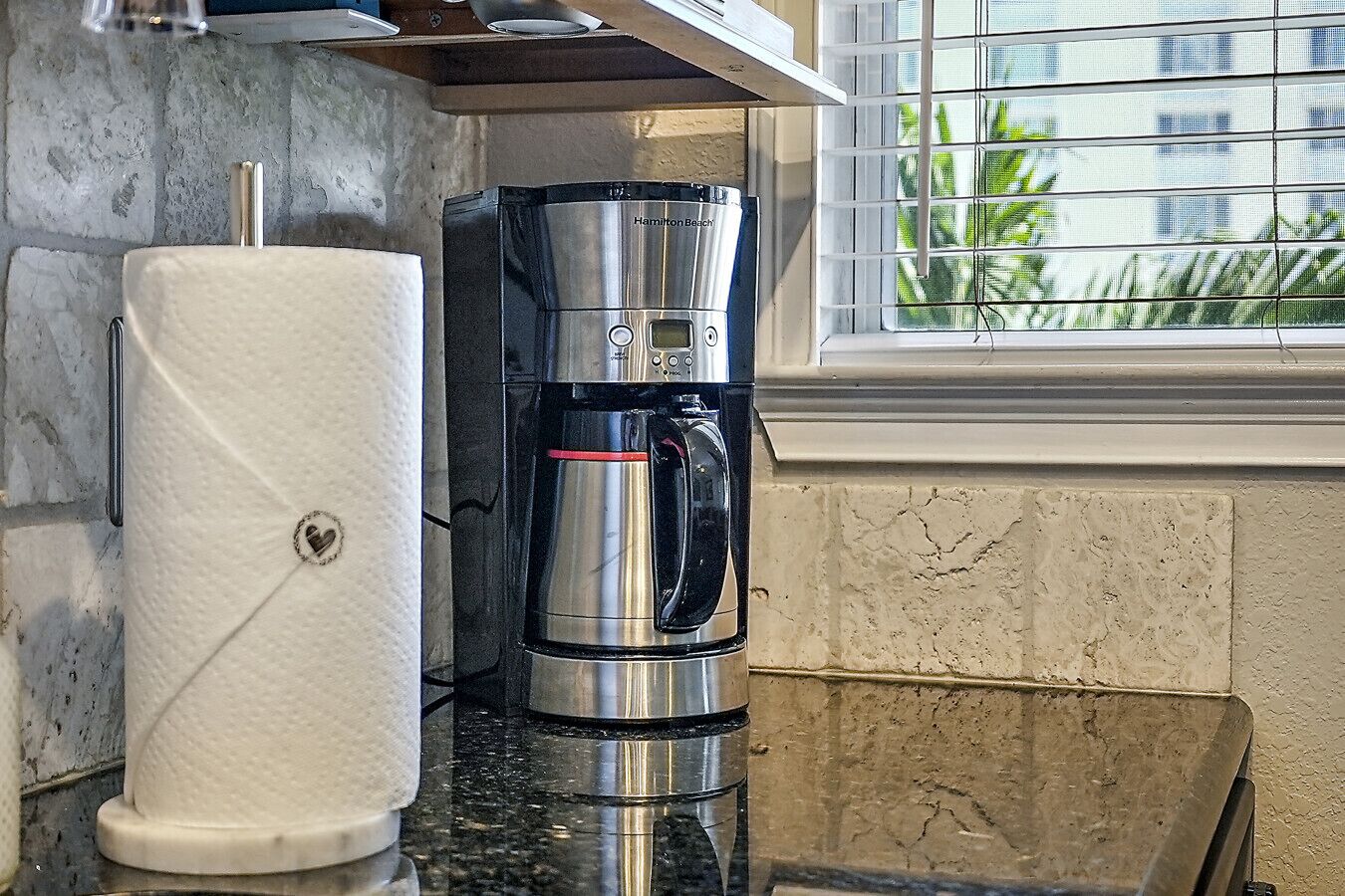 A kitchen with a coffee maker and a roll of paper towels on the counter.