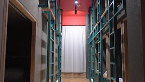 A narrow hallway with bunk beds on either side and a white curtain at the end. - ELE Cabin Shinjuku Kabukicho (Tokyo)