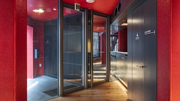 A corridor with a glass door leading to a reception area, a lounge, and a restroom.