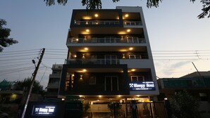 A multi-story hotel with illuminated signage, balconies, and a gated entrance.