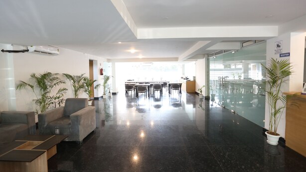 A modern lobby with a reception desk, seating area, and a glass wall.