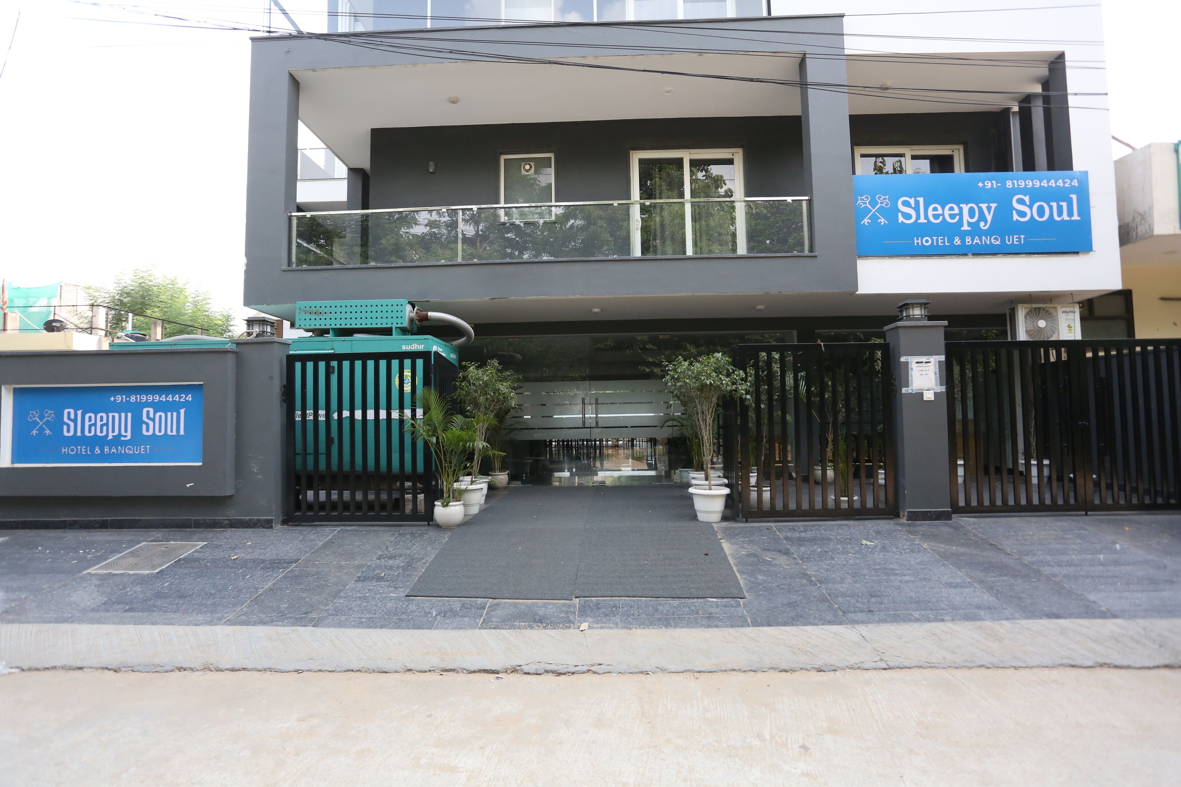 A modern building with a sign for "Sleepy Soul Hotel & Banquet" and a gated entrance.