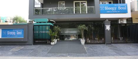 Un edificio moderno con un letrero que dice “Sleepy Soul Hotel & Banquet” y una entrada con portones.