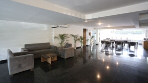 A spacious lobby with a grey sofa set, a coffee table, and potted plants.