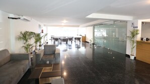 A modern lobby with a reception desk, seating area, and a glass partition.