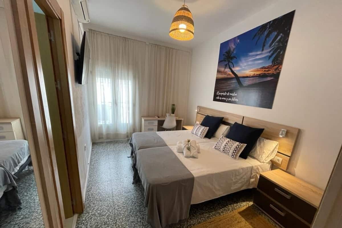 Een hotelkamer met een bed, nachtkastjes, een lamp, een schilderij en uitzicht op het strand.
