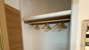 A walk-in closet with wooden shelves and hangers. - Hostal Ventura Premium  (Alicante)