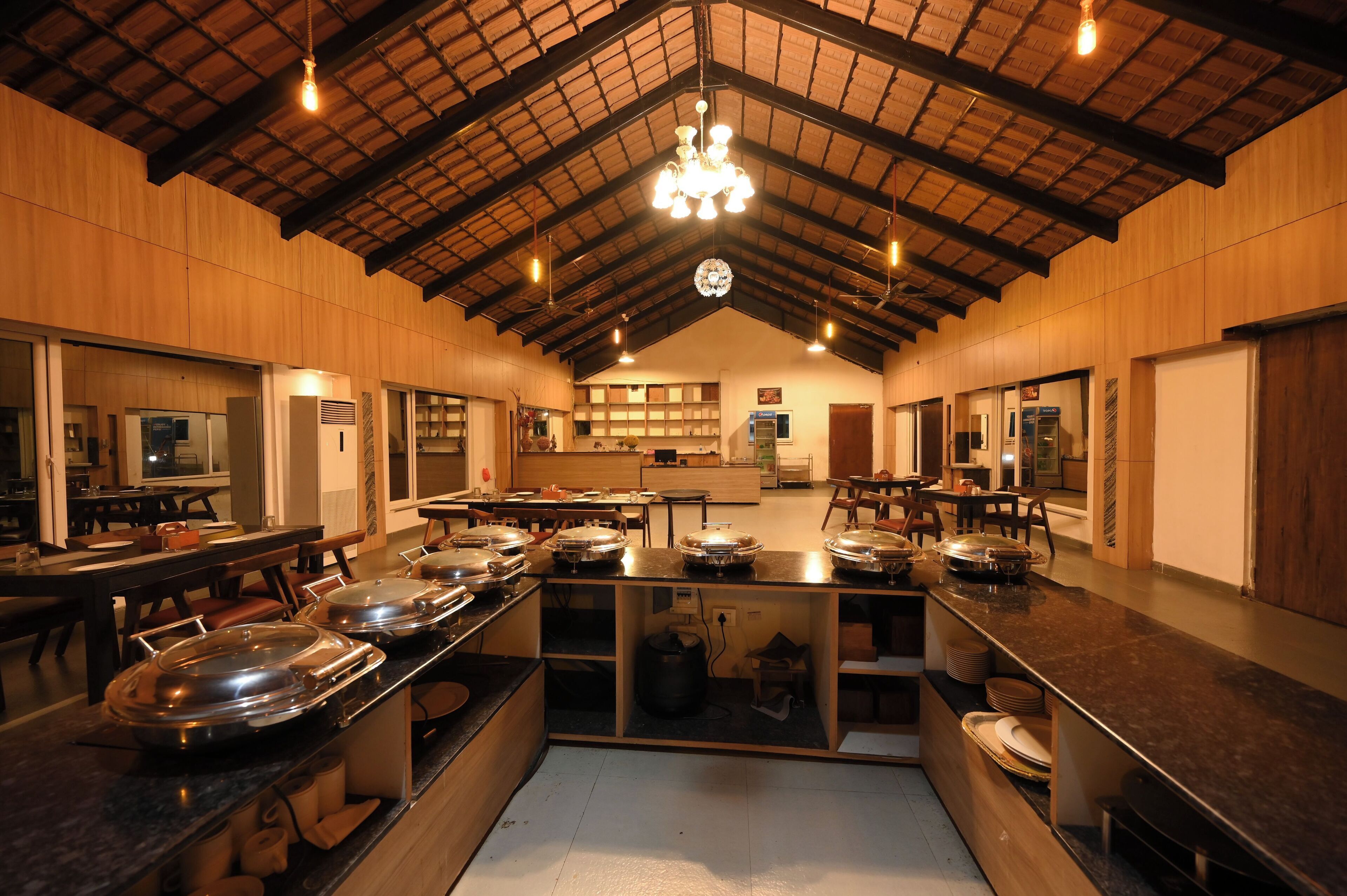 Una cocina amplia con paredes de madera, techo alto y una isla central con diversos electrodomésticos y utensilios de cocina.