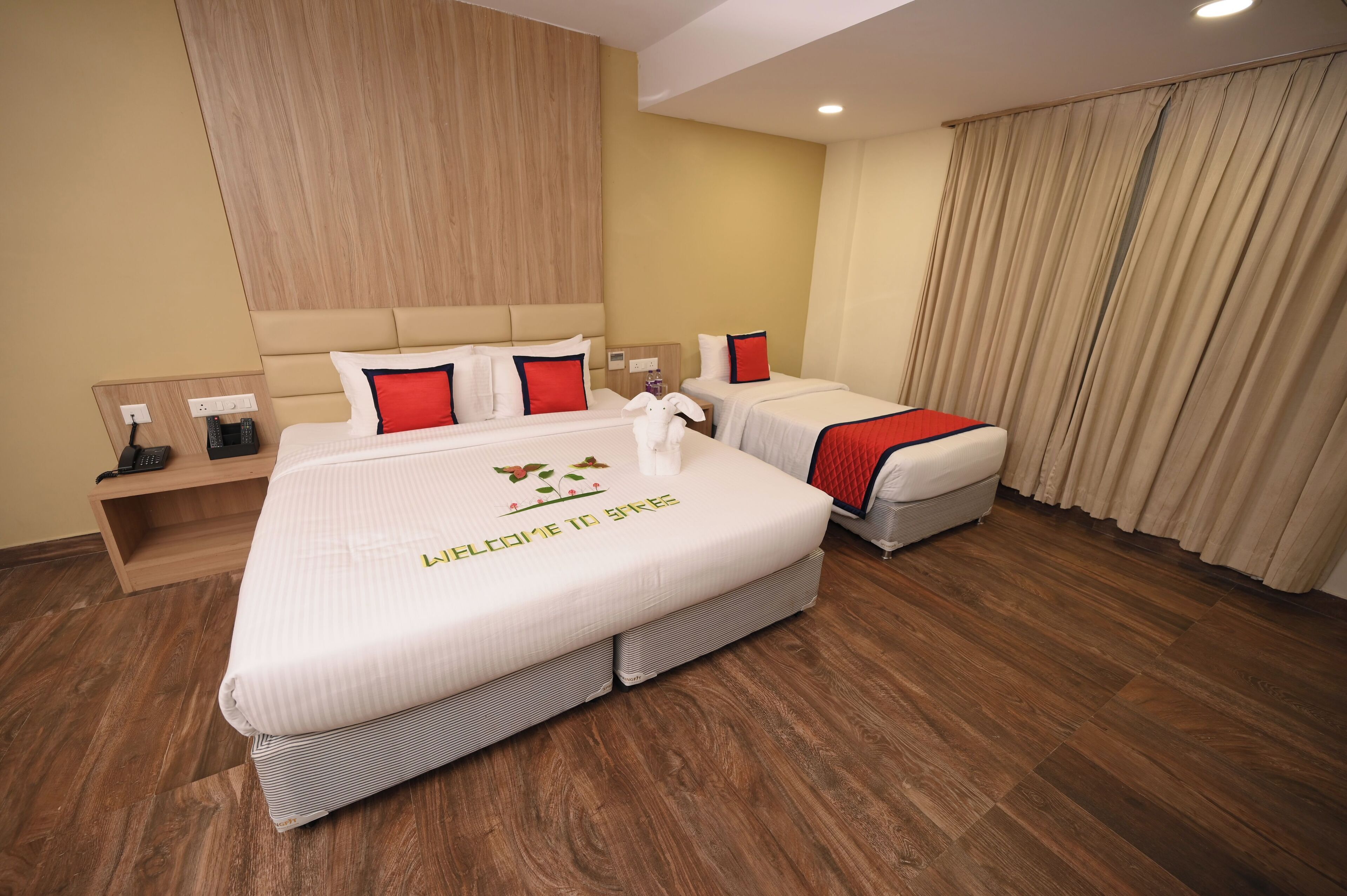 A hotel room with a large bed, two bedside tables, a wooden headboard, and a curtain.