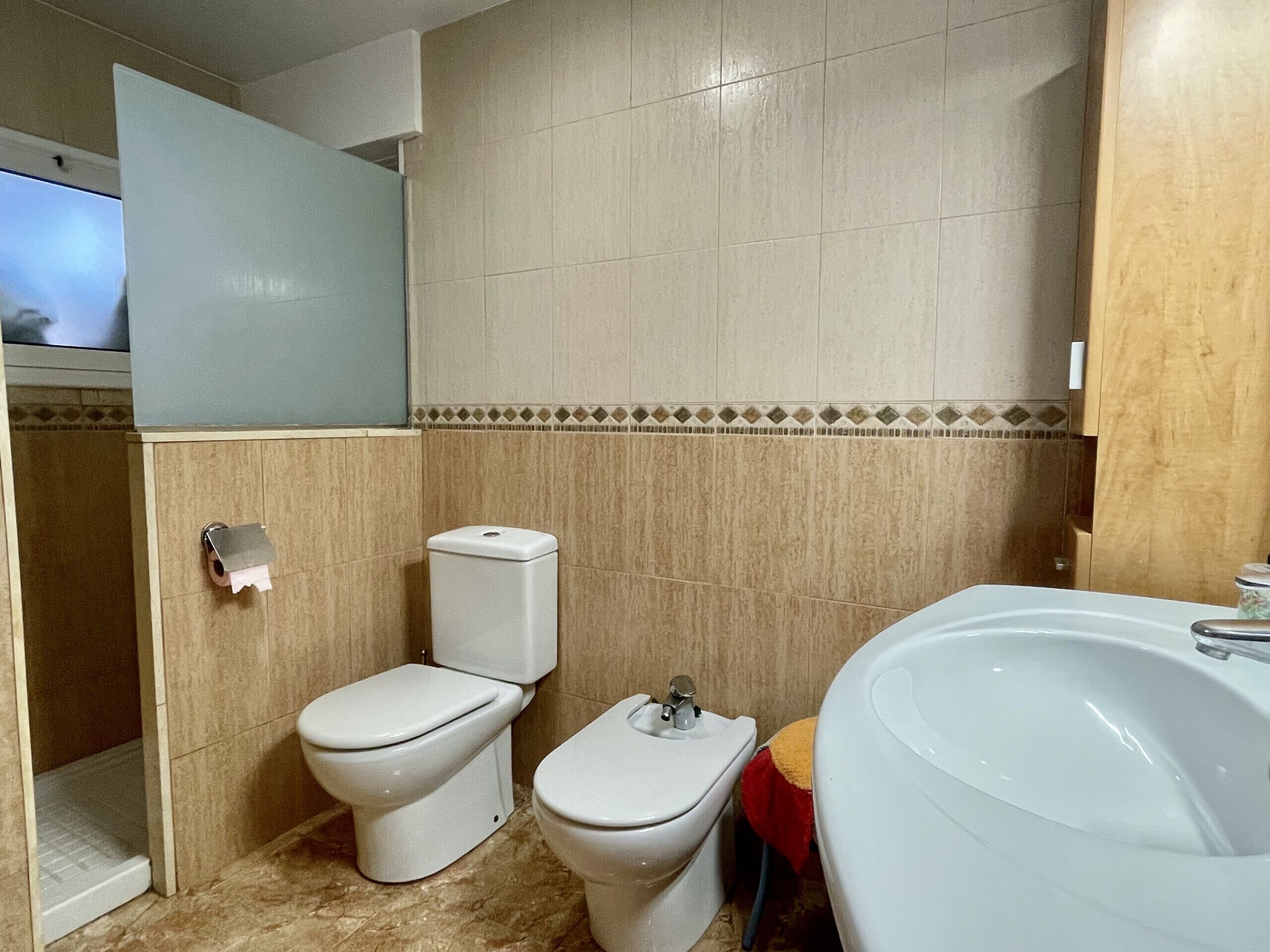 A bathroom with two toilets, a sink, and a shower.