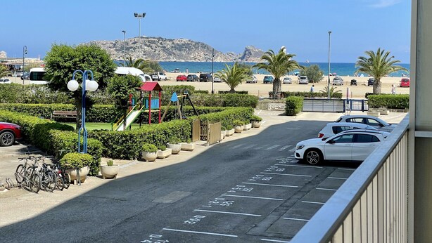 A parking area with cars, a playground, and a view of the beach and mountains. - ROCAMAURA I D 1-2 (Estartit)