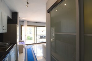 Una cucina moderna con piano cottura, mobili e una porta vetrata scorrevole che dà su un balcone.