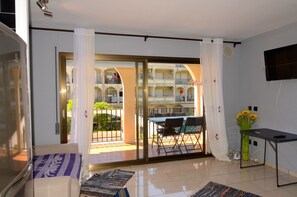 A room with a sliding glass door leading to an outdoor balcony, a flat-screen TV mounted on the wall, and a small table with chairs. - JARDINS DEL MAR 006 (Estartit)