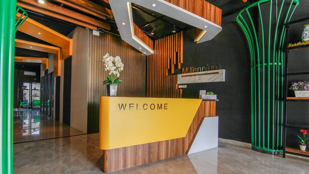 Una recepción con un cartel de 'WELCOME', paneles de madera y una planta en maceta.