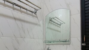Un baño con pared de azulejos de mármol blanco, un lavabo de cristal con grifo cromado y cabina de ducha con paredes de cristal.