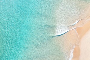 Une plage à l’eau turquoise et limpide, bordée d’un rivage sablonneux.
