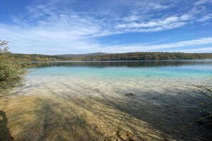 A clear lake with a forested shoreline and distant hills.