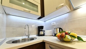 Una cuina moderna amb un rentaplatets d'acer inoxidable, una cafetera i un plat de fruita al taulell.