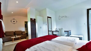 Habitació d'hotel amb un llit, un sofà, un escriptori i un rellotge a la paret.
