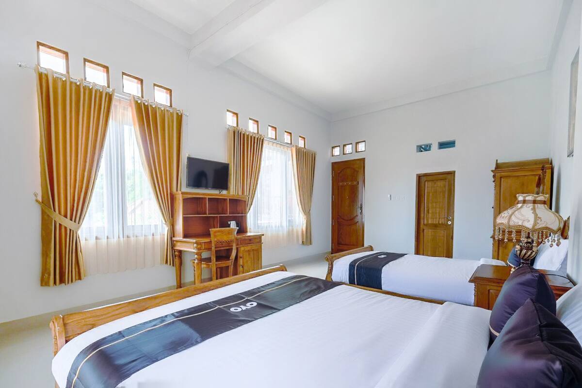 A hotel room with two beds, a desk, a TV, and a wardrobe.