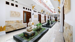 Un pasillo de hotel con una estatua, paneles decorativos en la pared y una fuente de agua.