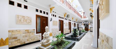 Ein Hotelkorridor mit einer Statue, Wandpaneelen und einer Wasserspielen.