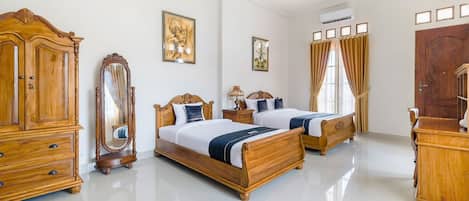 A spacious bedroom with two wooden beds, a large wardrobe, a mirror, and a chandelier.