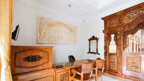 Una habitación con un escritorio de madera, una silla, un armario y una puerta de madera decorativa.