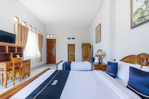 Una habitación de hotel con cama, escritorio, televisor y armario.