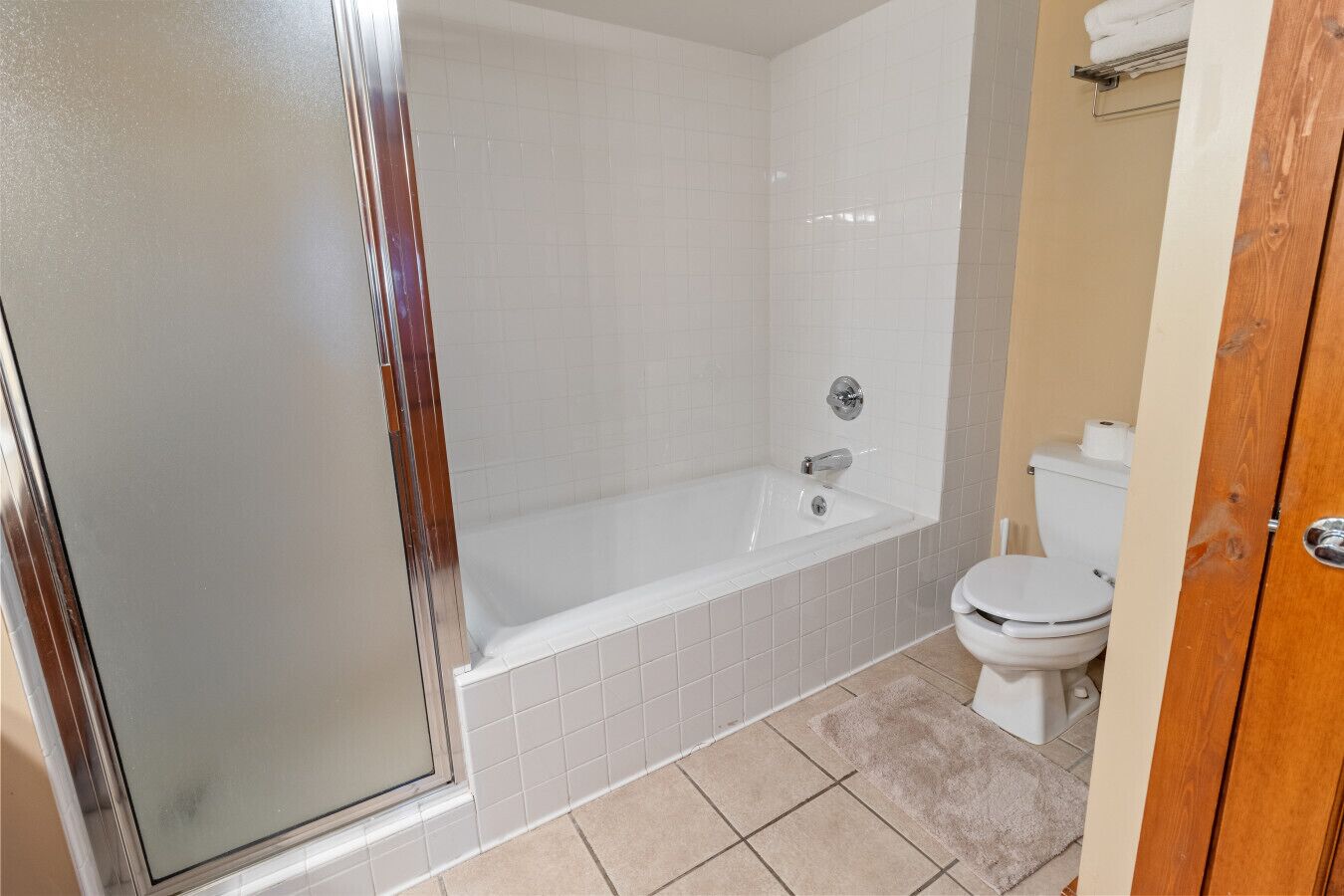 Et badeværelse med badekar, toilet og brusekabine i glas.