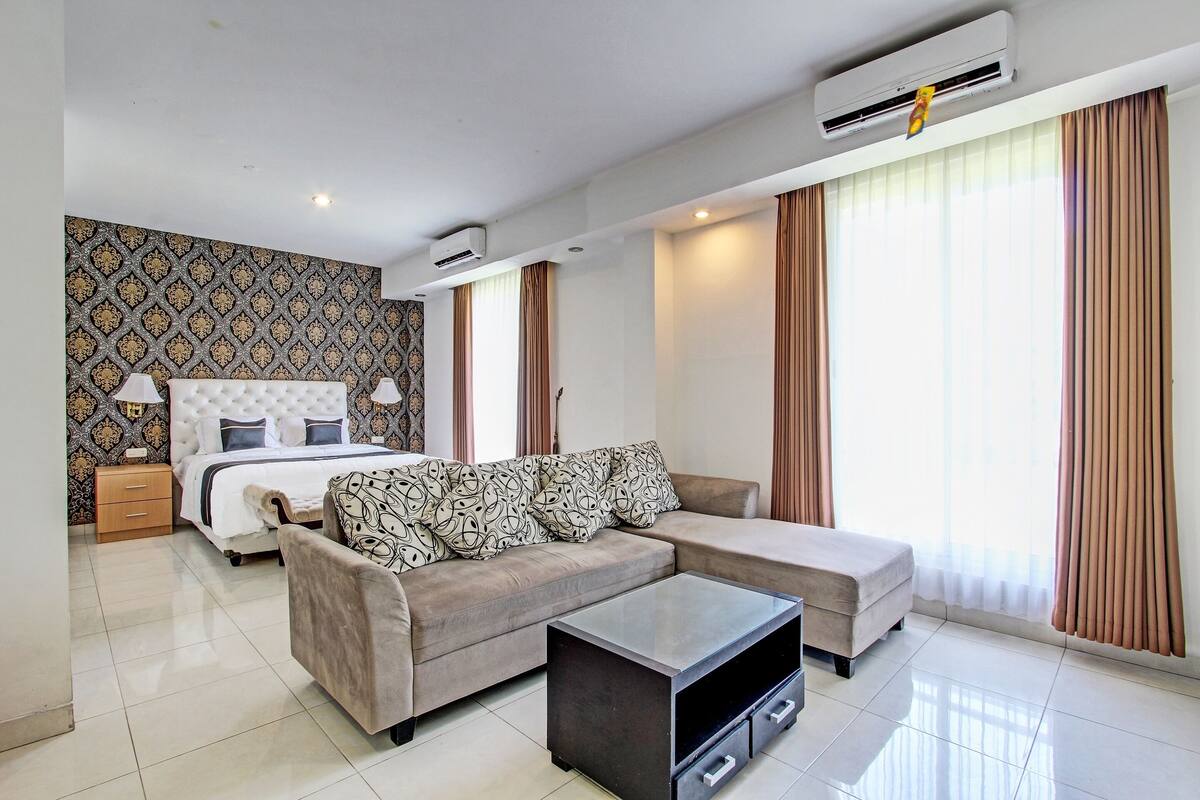 Una habitación de hotel moderna con cama, sofá y una mesita de centro.