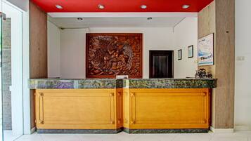 A reception area with a wooden reception desk, a large wall carving, and framed pictures on the wall.