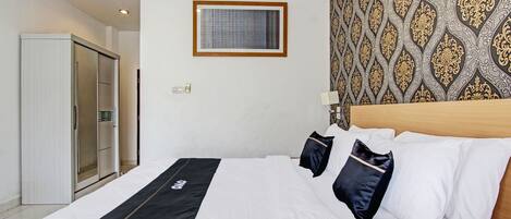 A hotel room with a bed, a wardrobe, and a patterned wall.