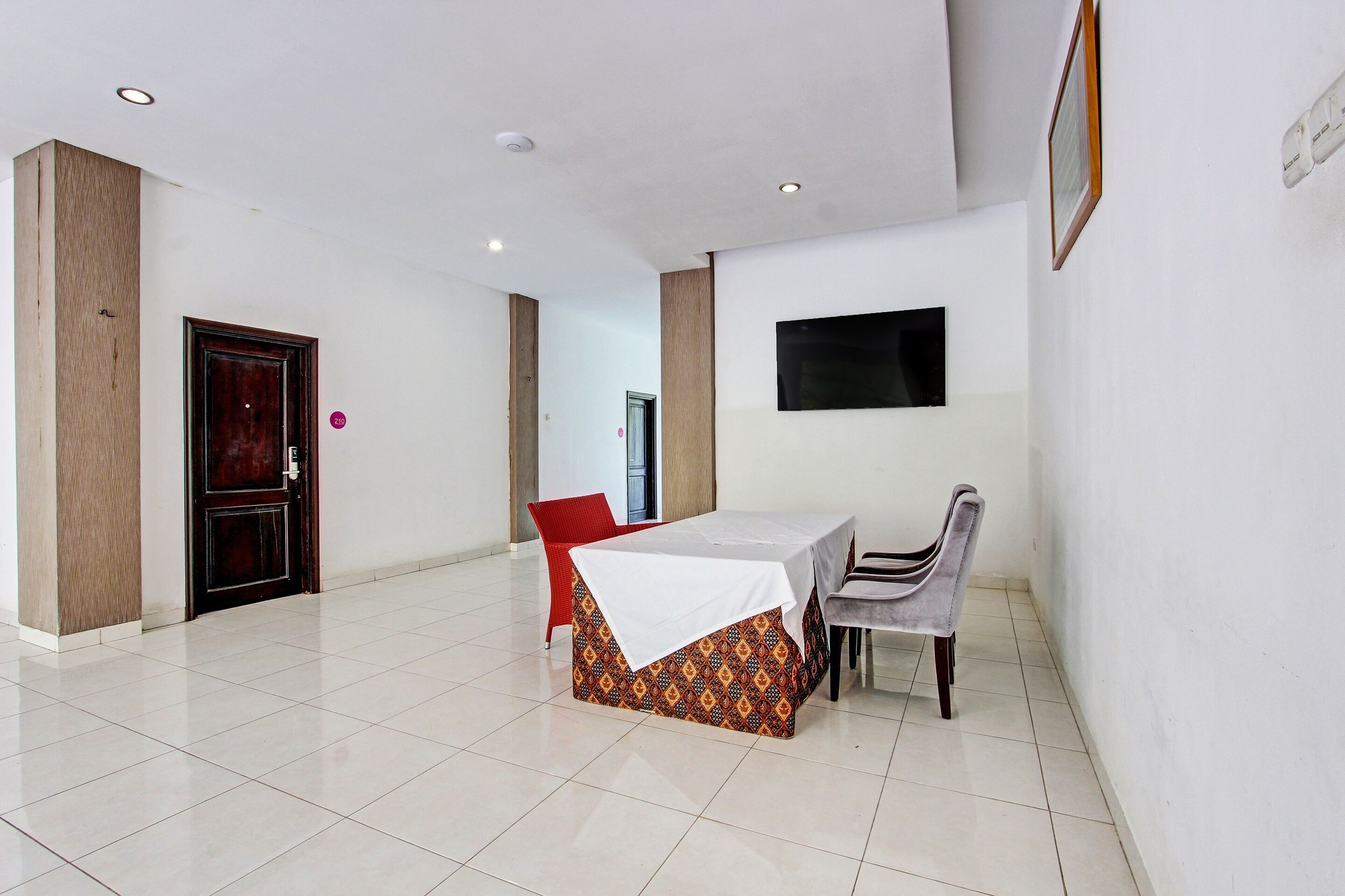 A dining area with a table and chairs, a wooden door, and a wall-mounted TV.