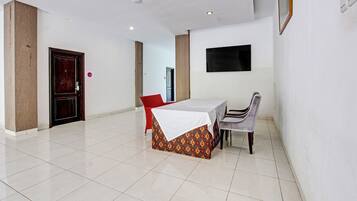 A dining area with a table and chairs, a wooden door, and a wall-mounted TV.