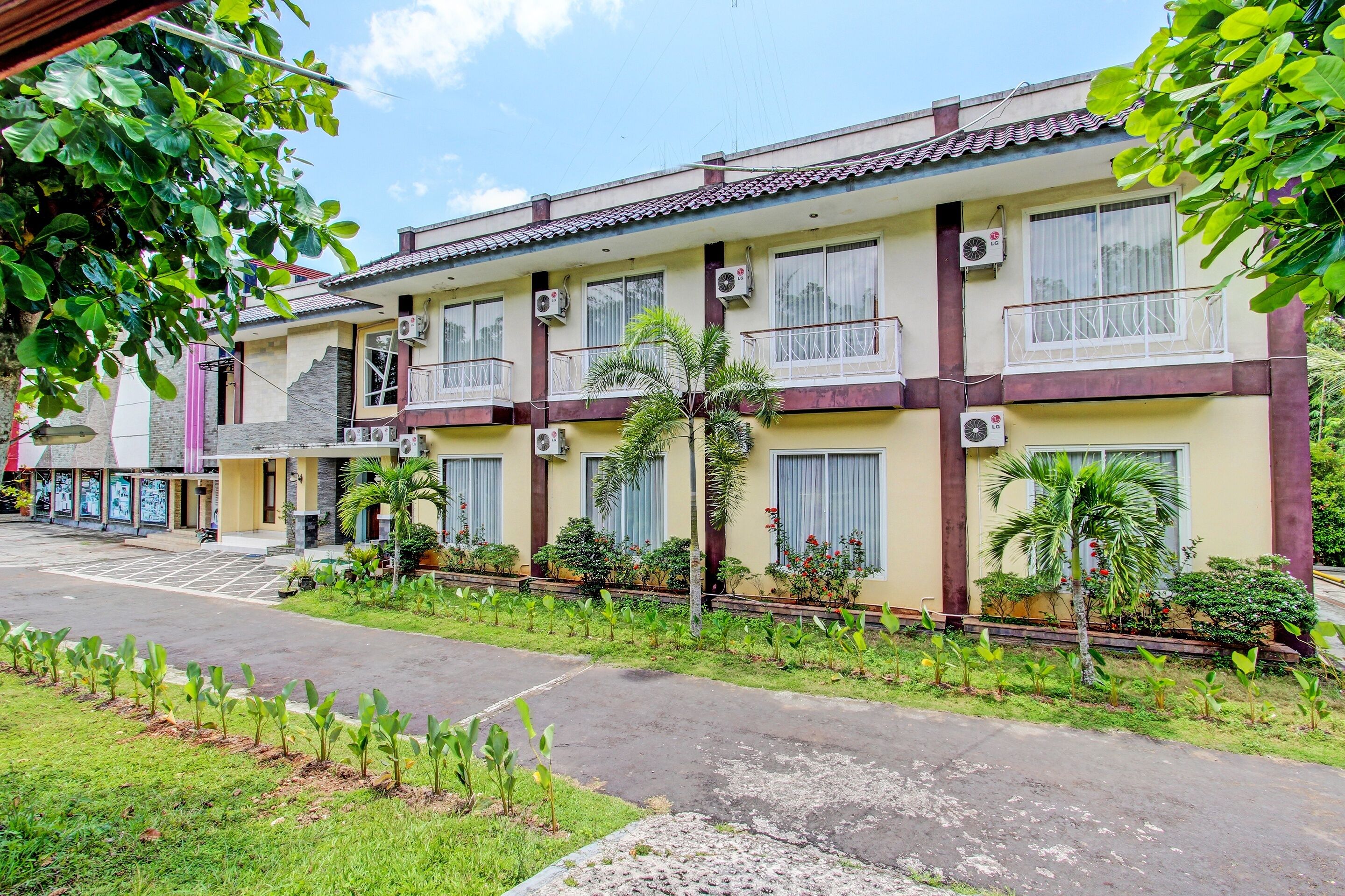 A multi-story building with air conditioning units, balconies, and a well-maintained garden area.