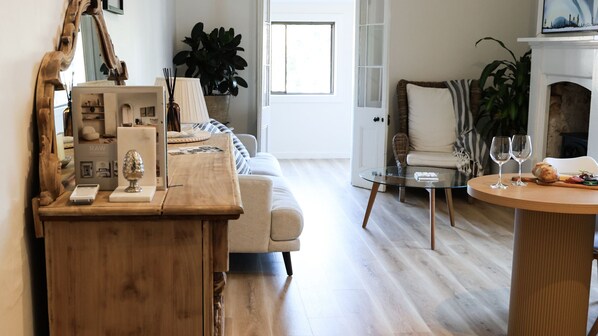 Una sala de estar con una mesa de centro de madera, una mesa de vidrio, un sofá y una chimenea.