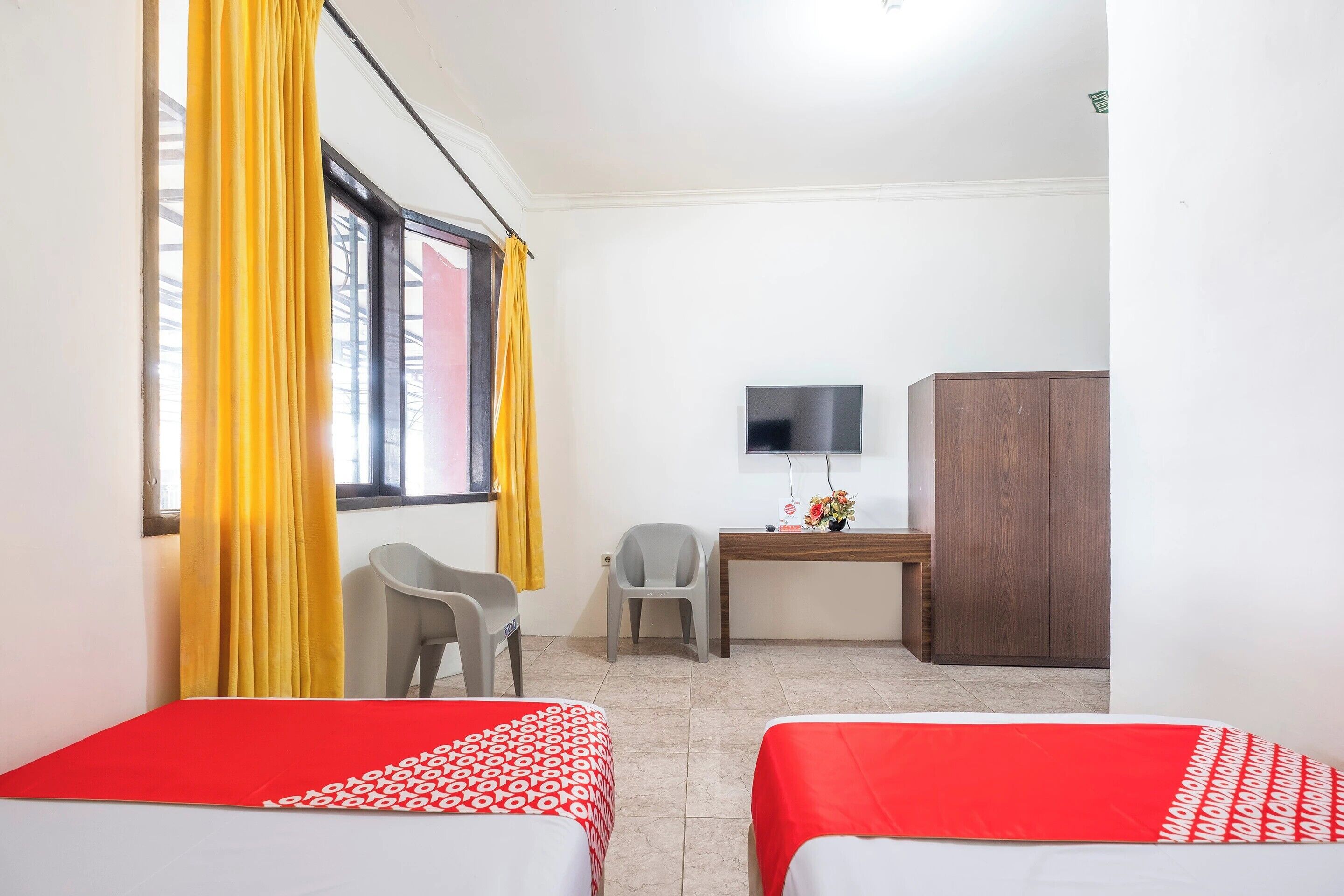A room with two beds, a desk, a TV, and a wardrobe.