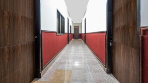 Un pasillo con puertas de madera y paredes rojas, que conduce a una puerta al final.