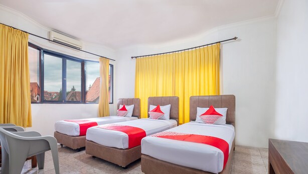 Habitación de hotel con tres camas, un escritorio y una silla.