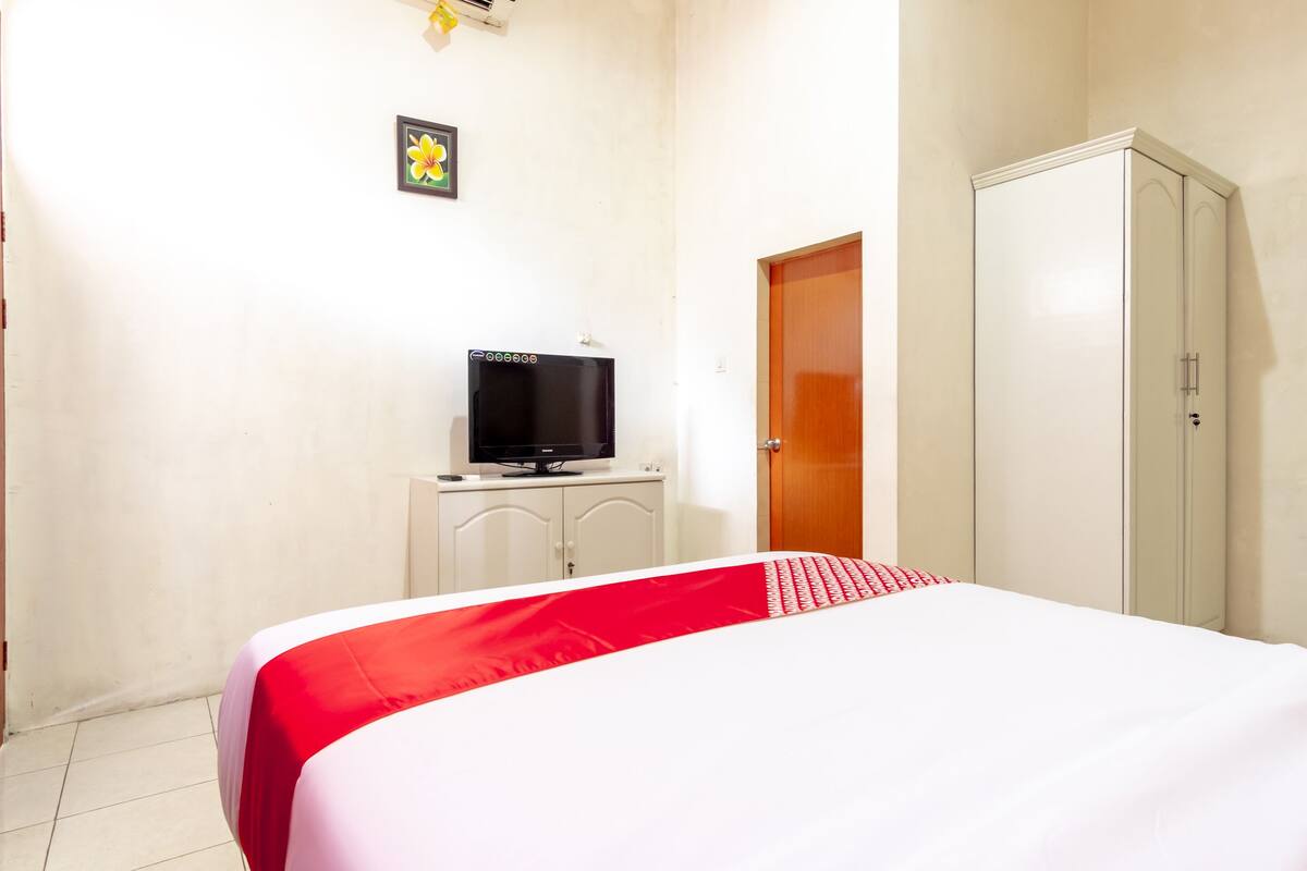 A hotel room with a bed, a television on a cabinet, and a wardrobe.