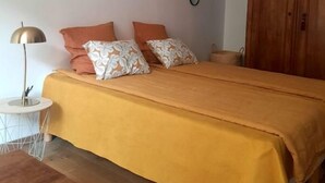 Une chambre à coucher avec un lit, une armoire en bois, une petite table ronde et une lampe.