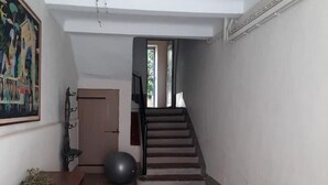 Un hall d’entrée spacieux, doté d’un sol carrelé, d’un banc en bois, d’un grand ballon d’exercice et d’un escalier menant à un autre niveau.