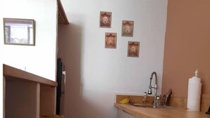 Une cuisine de taille réduite, dotée d’un plan de travail en bois, d’un évier, d’une cuisinière et d’une poubelle.