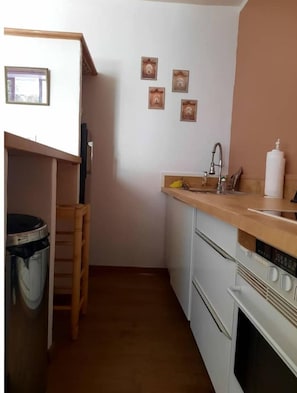 A compact kitchen with a wooden countertop, a sink, a stove, and a trash bin. - Studio Indépendant Avec Cour (Cotignac)