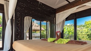 A bed with a view of a thatched-roof structure and lush greenery outside. - Villa Jempiring (Banjar)