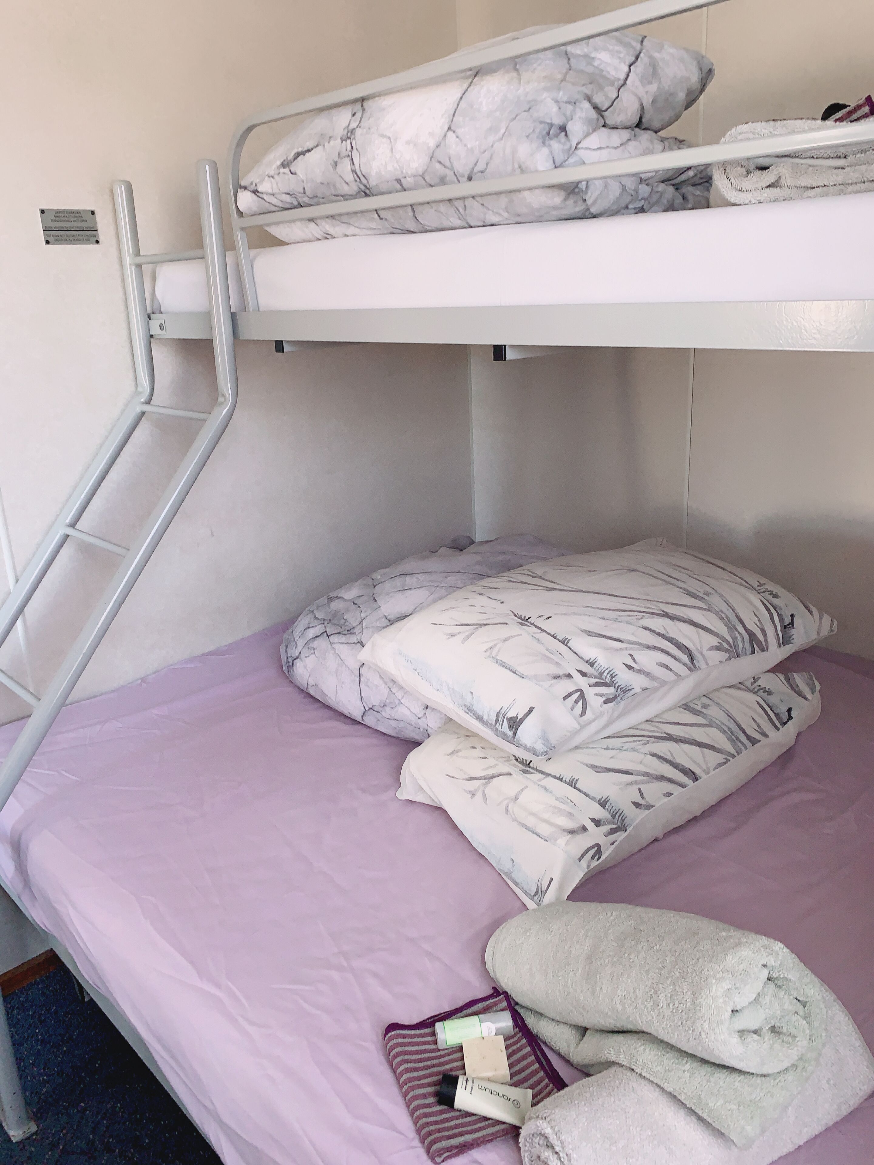 A bunk bed with a ladder, a purple mattress, and pillows with a leaf pattern.